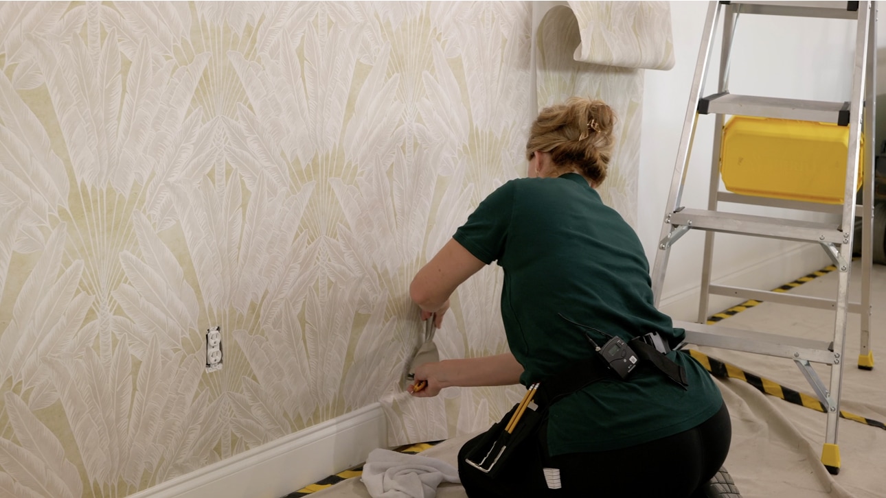 Professional installer applying wallpaper to a prepared wall